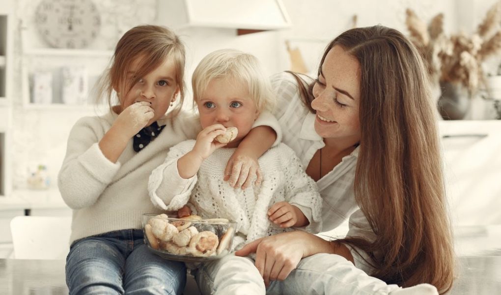 Mother and kids enjoying cookies in a warm, cozy kitchen setting.