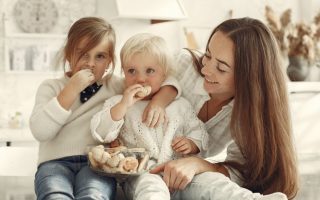 Mother and kids enjoying cookies in a warm, cozy kitchen setting.