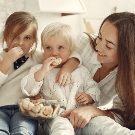 Mother and kids enjoying cookies in a warm, cozy kitchen setting.