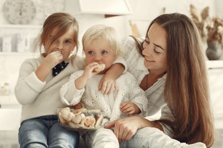 Mother and kids enjoying cookies in a warm, cozy kitchen setting.
