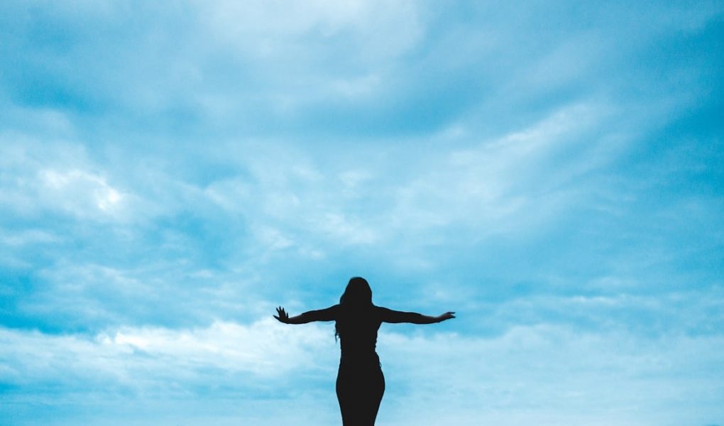 silhouette photography of woman raising her hands