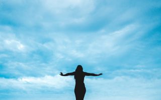 silhouette photography of woman raising her hands