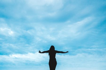 silhouette photography of woman raising her hands