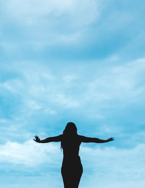 silhouette photography of woman raising her hands