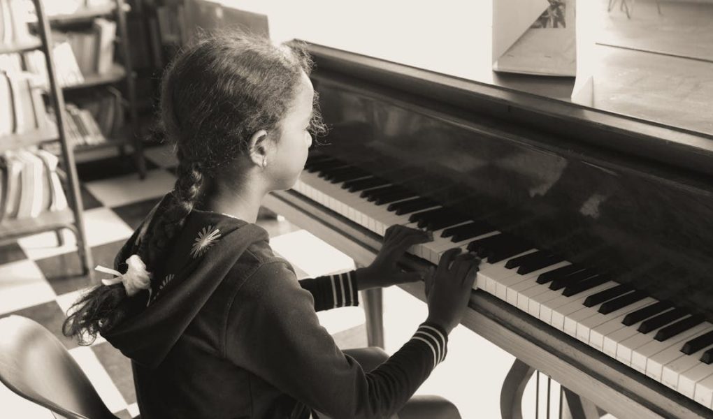 A young girl practicing piano indoors in a cozy setting, focused and serene.