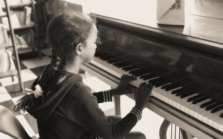 A young girl practicing piano indoors in a cozy setting, focused and serene.