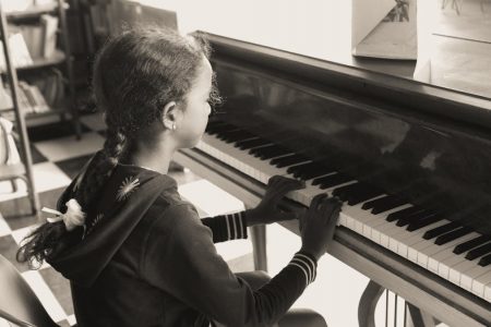 A young girl practicing piano indoors in a cozy setting, focused and serene.