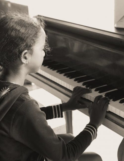 A young girl practicing piano indoors in a cozy setting, focused and serene.